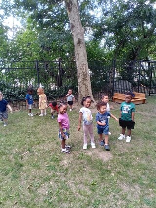 Children playing outside at a Glenbrook CT daycare, surrounded by trees and greenery.