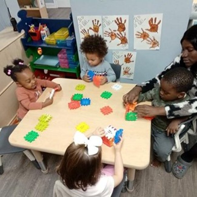 Infants playing on the floor with toys at a daycare in Glenbrook CT.