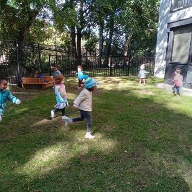 Children playing outdoors in a daycare near Norwalk CT on a sunny day.