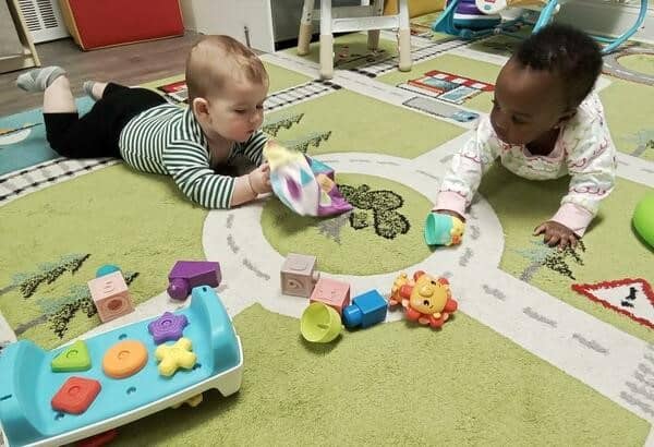 Infants playing on the floor with toys at a daycare in Glenbrook CT.