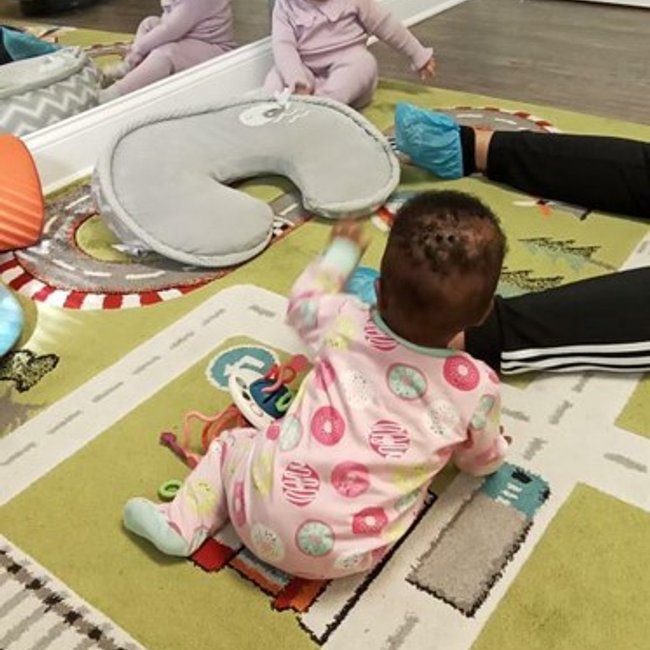 Infant playing on colorful mat at daycare in Glenbrook, CT.